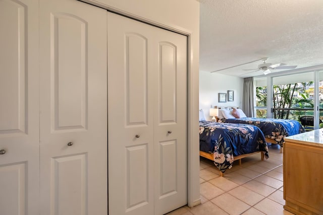 bedroom featuring light tile patterned floors, a ceiling fan, and a textured ceiling