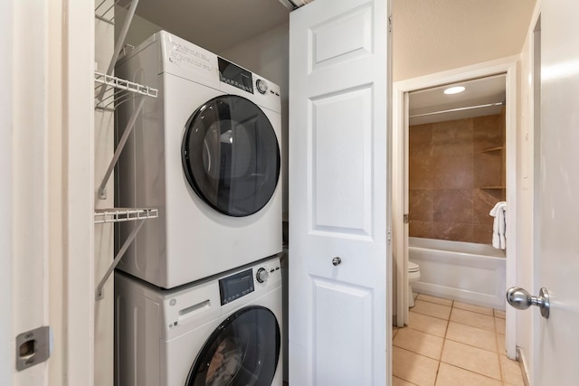 laundry area with recessed lighting, laundry area, light tile patterned floors, and stacked washer and dryer