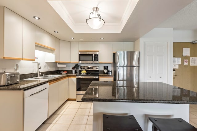 kitchen with a sink, stainless steel appliances, light tile patterned flooring, and a kitchen bar