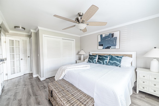 bedroom featuring a closet, a ceiling fan, wood finished floors, baseboards, and ornamental molding