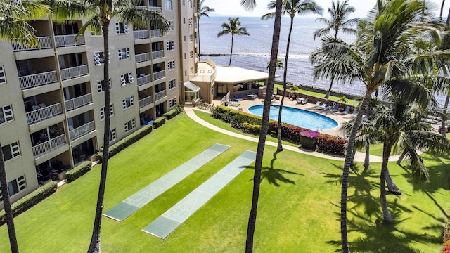 community pool with a water view, a patio, and a yard