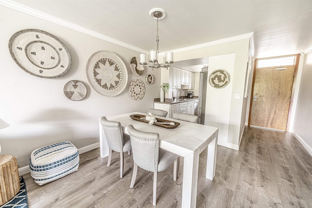 dining room with ornamental molding, a notable chandelier, and light wood finished floors