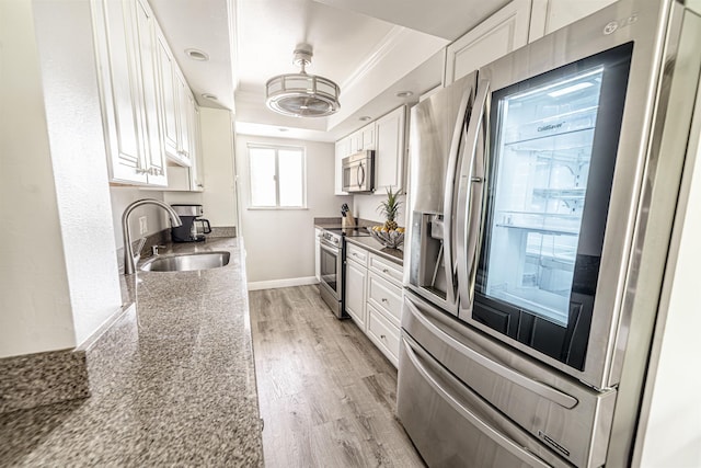 kitchen with a tray ceiling, white cabinetry, a sink, and stainless steel appliances
