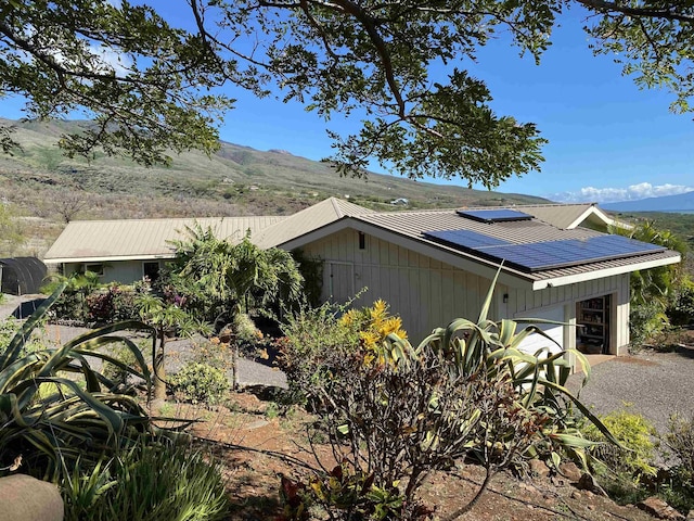 view of property exterior with solar panels, a garage, and a mountain view