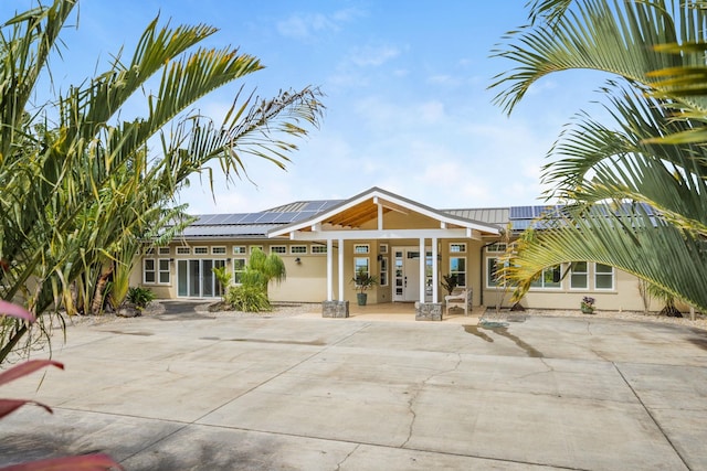 exterior space featuring roof mounted solar panels, stucco siding, and metal roof