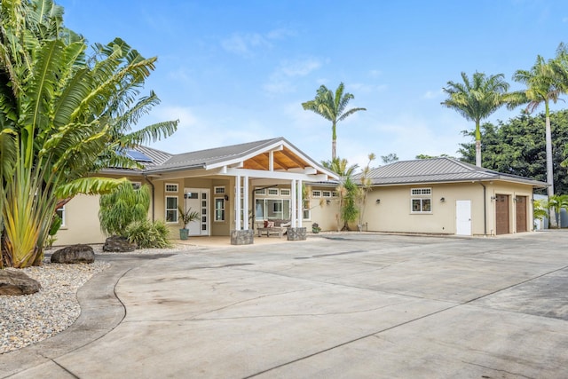 view of front of home with a standing seam roof, stucco siding, concrete driveway, roof mounted solar panels, and metal roof