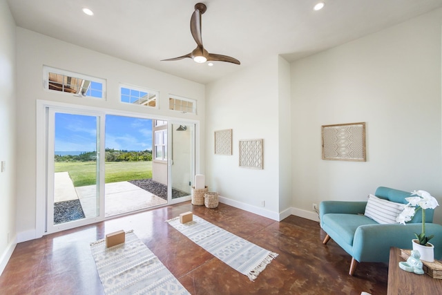 living area featuring a ceiling fan, recessed lighting, baseboards, concrete flooring, and a towering ceiling