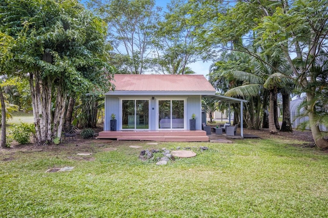 rear view of property with a lawn, metal roof, and a deck