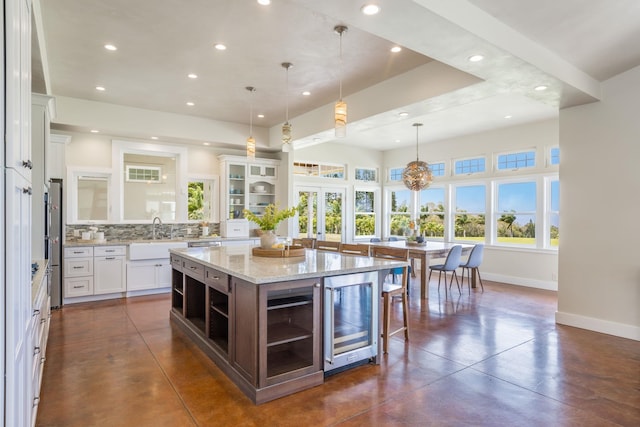 kitchen with open shelves, concrete floors, beverage cooler, french doors, and a sink