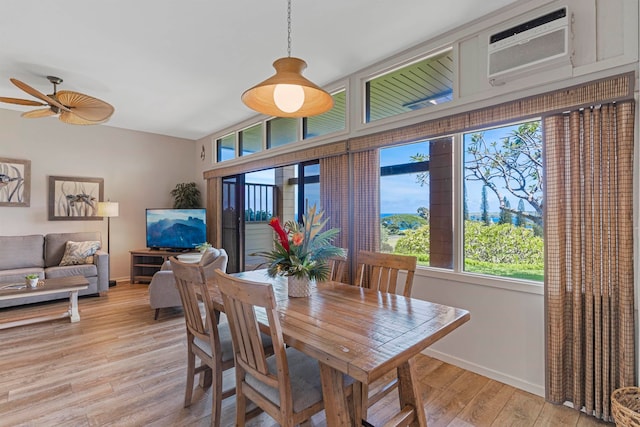 dining area featuring light wood-type flooring, an AC wall unit, and ceiling fan