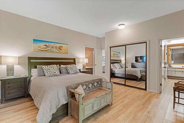 bedroom with light wood-type flooring, connected bathroom, and a closet