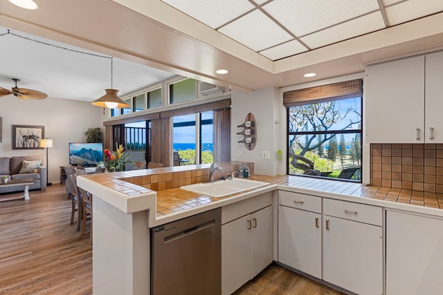 kitchen with white cabinets, a wealth of natural light, tile countertops, and sink