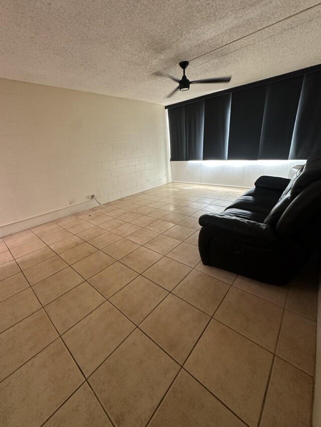 111 Kahului Beach Rd Unit A407, Kahului, HI 96732 - living room with tile patterned flooring, a textured ceiling, concrete block wall, and ceiling fan