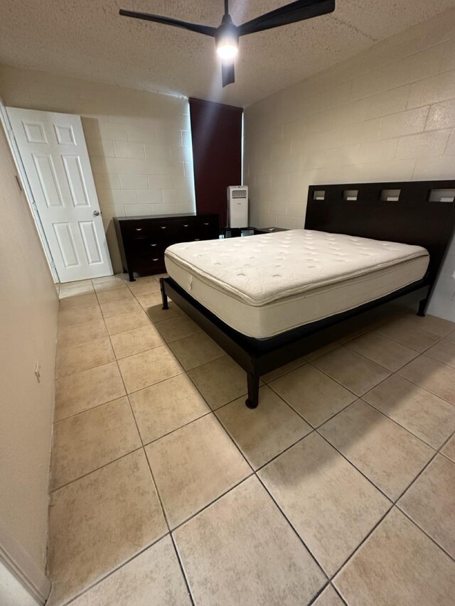 111 Kahului Beach Rd Unit A407, Kahului, HI 96732 - bedroom featuring a ceiling fan, concrete block wall, light tile patterned flooring, and a textured ceiling