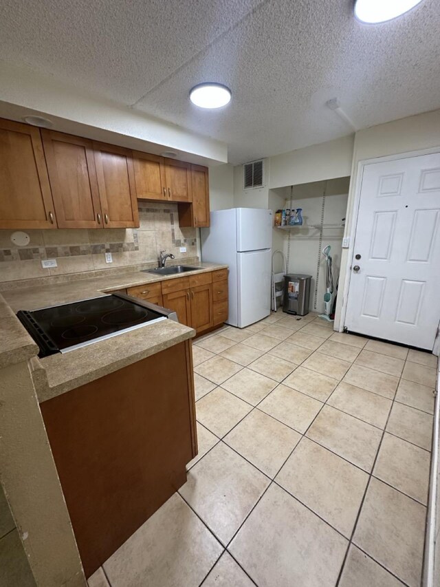 111 Kahului Beach Rd Unit A407, Kahului, HI 96732 - kitchen with a textured ceiling, freestanding refrigerator, visible vents, brown cabinetry, and a sink