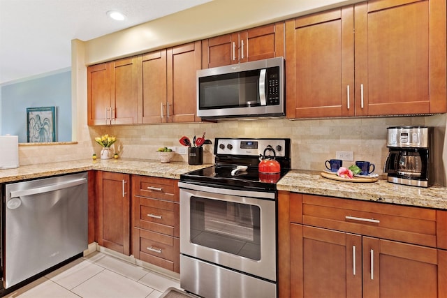 kitchen with light stone countertops, decorative backsplash, light tile patterned floors, and stainless steel appliances