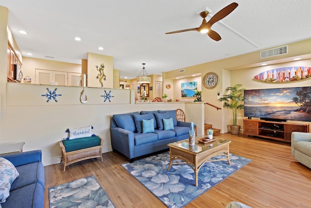 living room featuring ceiling fan, a textured ceiling, and light hardwood / wood-style flooring