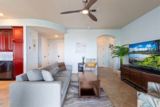 living room with a ceiling fan, light tile patterned floors, baseboards, visible vents, and arched walkways
