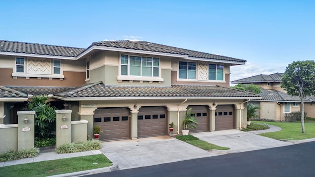 view of front of property with an attached garage, a tile roof, stucco siding, and driveway