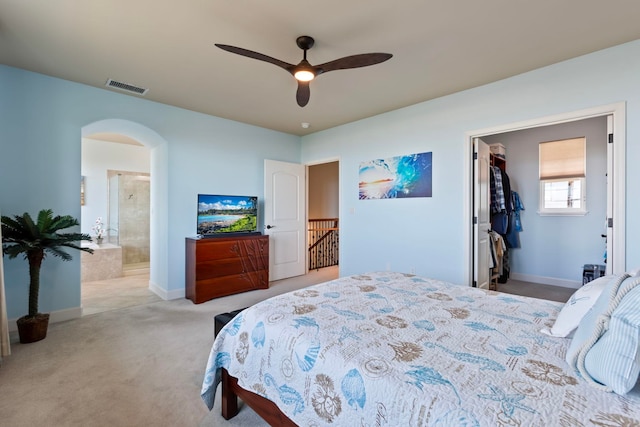 bedroom with a spacious closet, baseboards, carpet floors, arched walkways, and visible vents