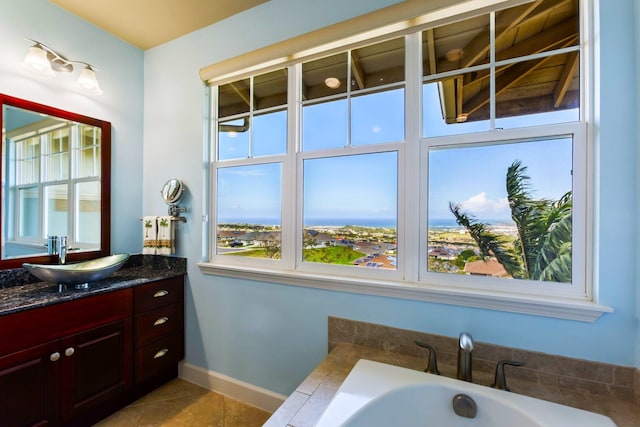 bathroom with a bathing tub, tile patterned floors, vanity, and baseboards