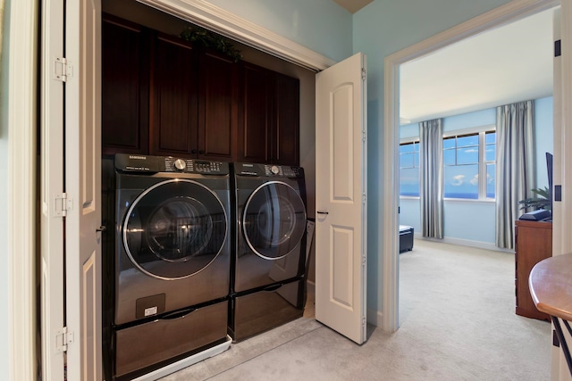 laundry room with cabinet space, washing machine and dryer, baseboards, and light carpet