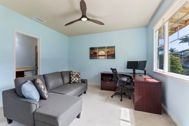 office area featuring light colored carpet, visible vents, baseboards, and a ceiling fan