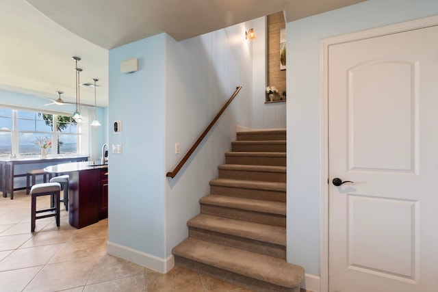 stairs featuring tile patterned floors, baseboards, and ceiling fan