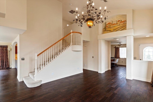 unfurnished living room featuring a towering ceiling, an inviting chandelier, and hardwood / wood-style floors