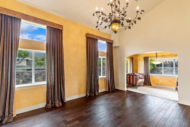 spare room with dark wood-type flooring, high vaulted ceiling, and plenty of natural light