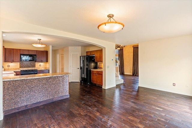 kitchen featuring kitchen peninsula, dark hardwood / wood-style floors, black appliances, and pendant lighting