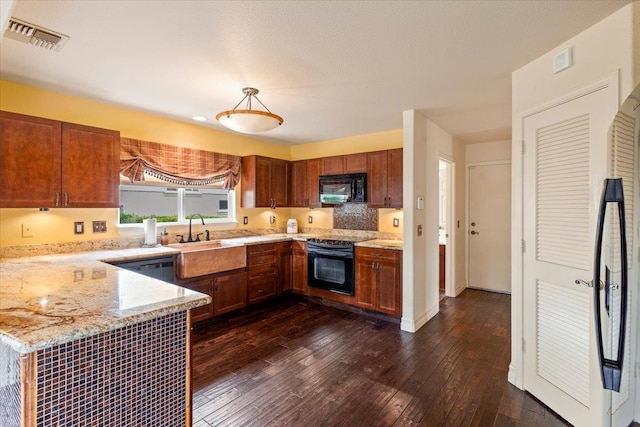 kitchen featuring light stone countertops, dark hardwood / wood-style floors, black appliances, pendant lighting, and sink