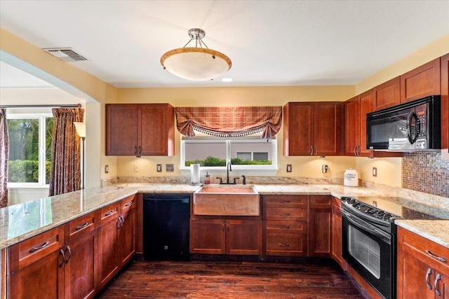 kitchen with dark wood-type flooring, kitchen peninsula, sink, black appliances, and light stone countertops