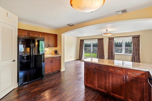 kitchen featuring dark hardwood / wood-style flooring, light stone countertops, hanging light fixtures, and black fridge with ice dispenser