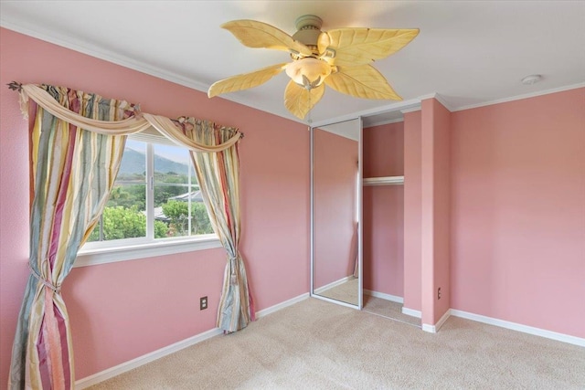 unfurnished bedroom with light carpet, a closet, crown molding, and ceiling fan