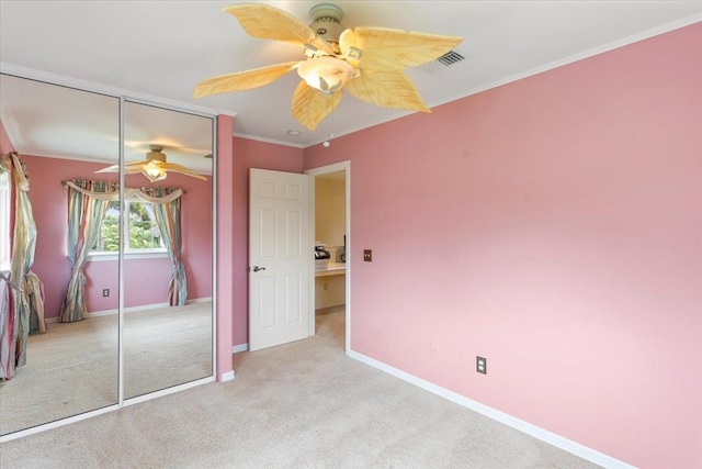 unfurnished bedroom with crown molding, light colored carpet, a closet, and ceiling fan