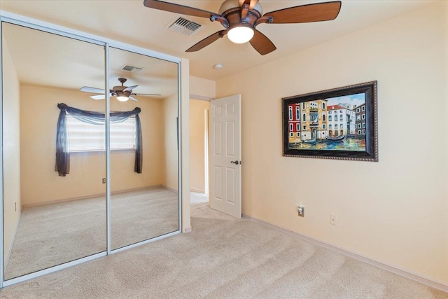 unfurnished bedroom with light carpet, a closet, and ceiling fan