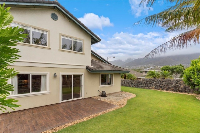 back of house with a mountain view and a yard