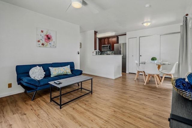 living room featuring ceiling fan, sink, and light hardwood / wood-style floors