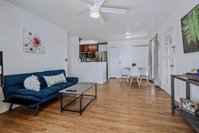 living room featuring ceiling fan and light hardwood / wood-style floors