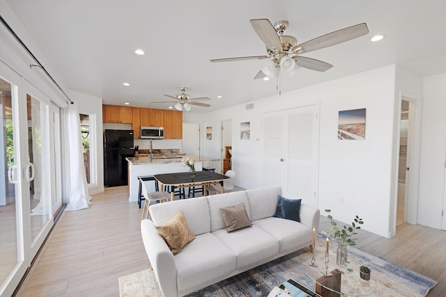 living room with light hardwood / wood-style floors and ceiling fan