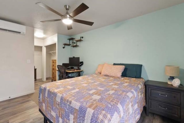 bedroom featuring ceiling fan, an AC wall unit, wood-type flooring, a spacious closet, and a closet