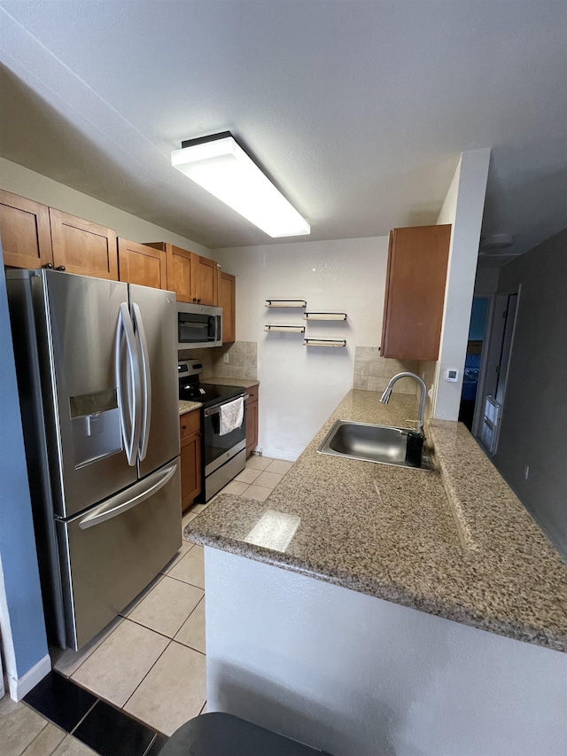 kitchen with light tile patterned flooring, sink, kitchen peninsula, stainless steel appliances, and decorative backsplash