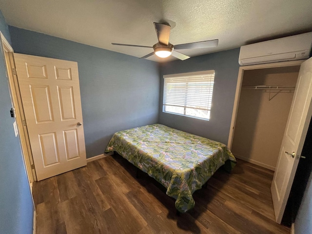 bedroom with an AC wall unit, ceiling fan, dark wood-type flooring, a textured ceiling, and a closet