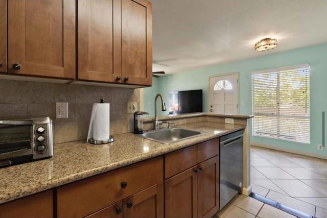 kitchen with tasteful backsplash, dishwasher, sink, light tile patterned floors, and light stone countertops