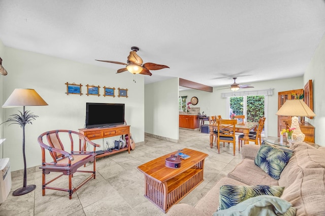 living room featuring a ceiling fan, a textured ceiling, and baseboards