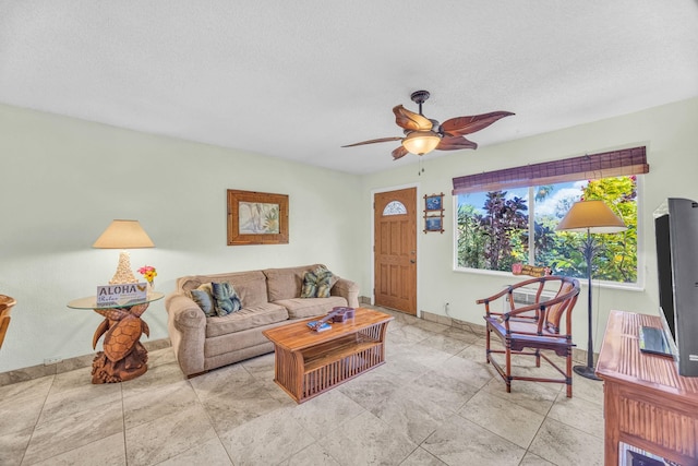 living area featuring baseboards, a ceiling fan, and a textured ceiling