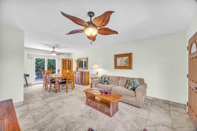 living area featuring baseboards and ceiling fan