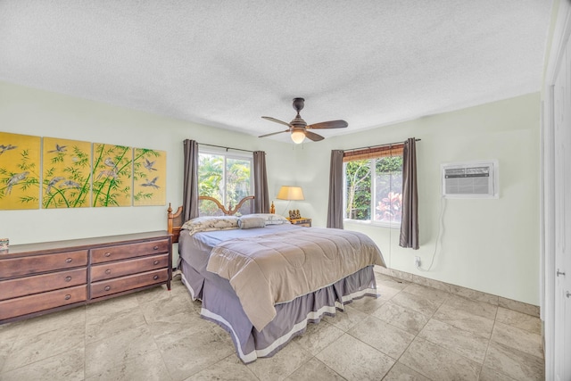 bedroom with baseboards, a textured ceiling, multiple windows, and a wall mounted AC