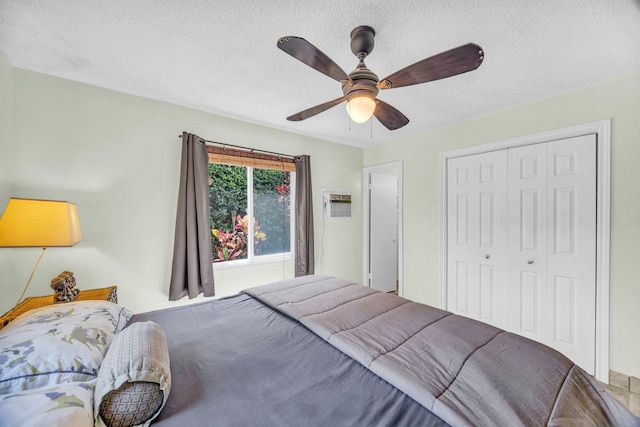 bedroom featuring a ceiling fan, a textured ceiling, a closet, and a wall mounted AC
